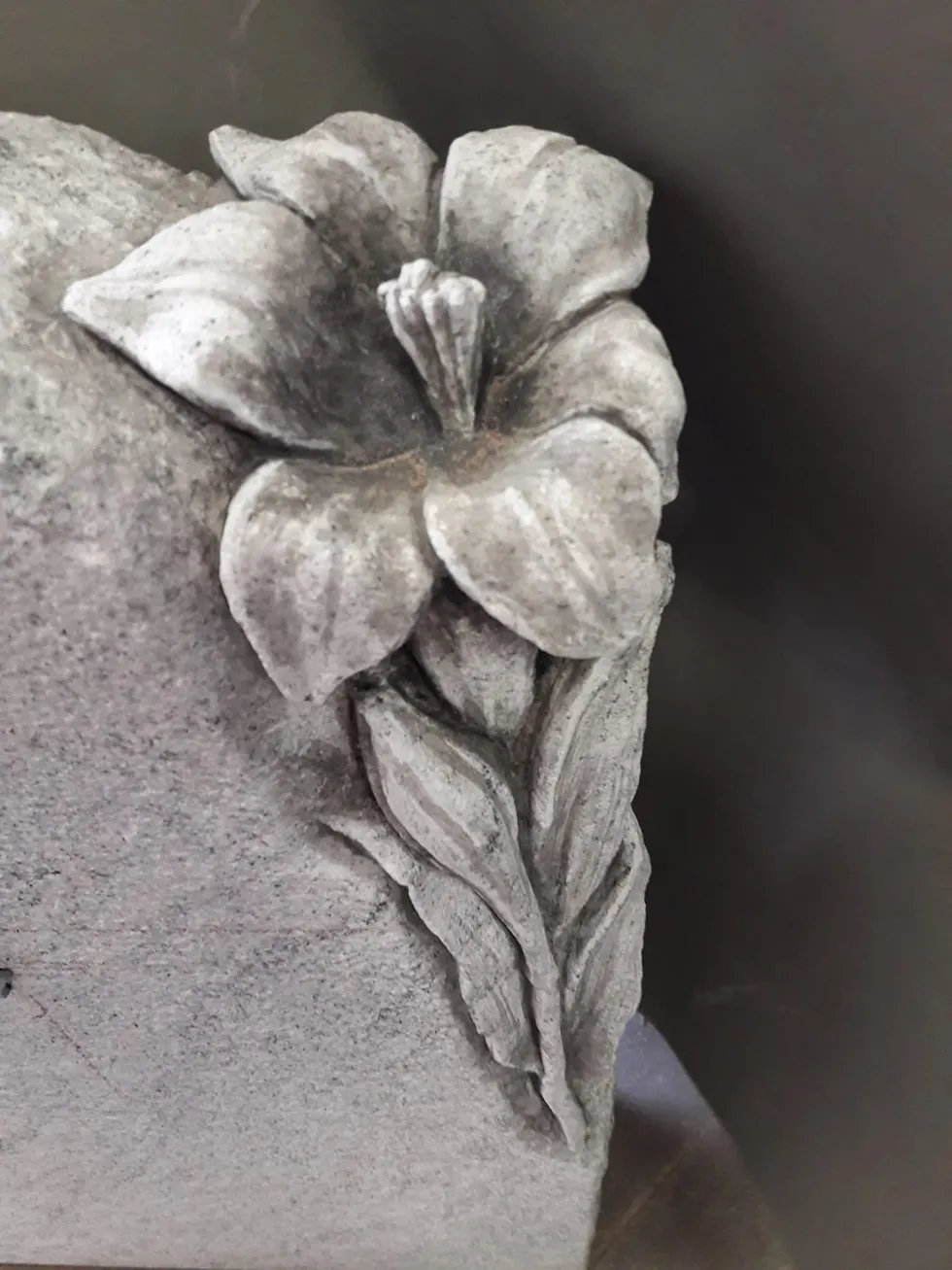 Nahaufnahme einer Blume aus Stein als Teil eines Grabsteins